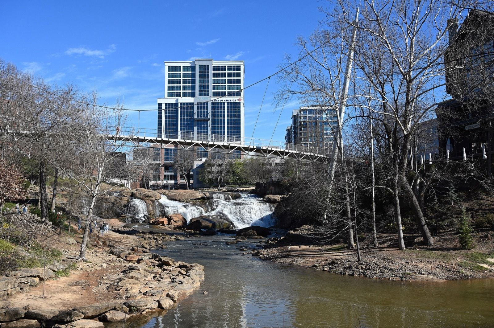 The Reedy River falls under the Liberty Bridge in Falls Park, with downtown Greenville behind it